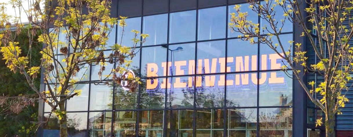 Transparent LED on a glass curtain wall in Paris showing BIENVENUE